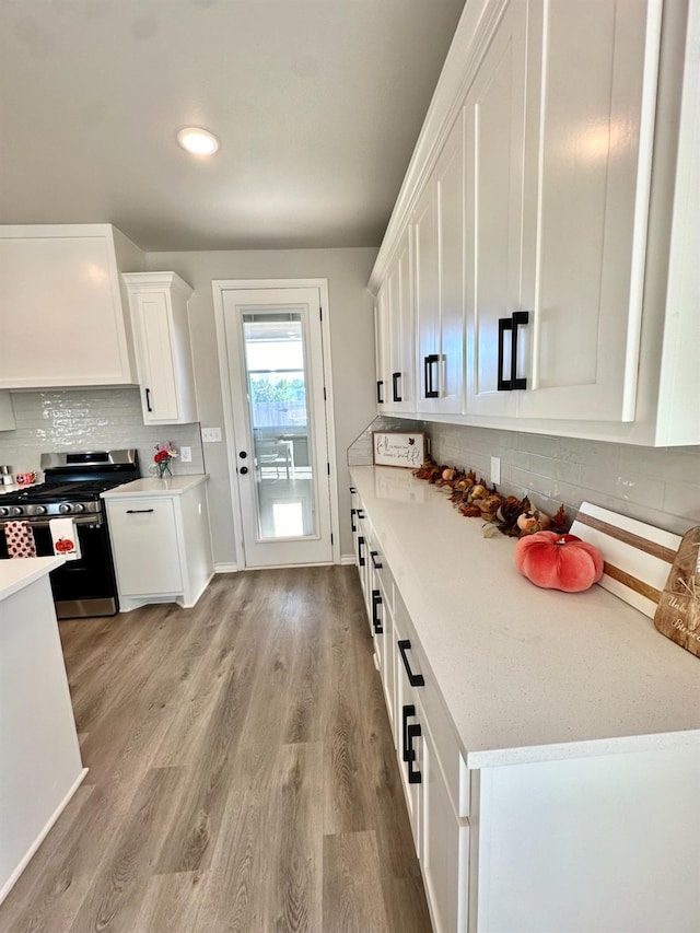 kitchen featuring backsplash, stainless steel stove, light hardwood / wood-style flooring, and white cabinets