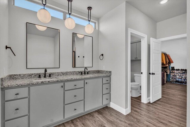 6803 52nd St, Lubbock, TX 79407 - full bath featuring wood finished floors, double vanity, toilet, and baseboards