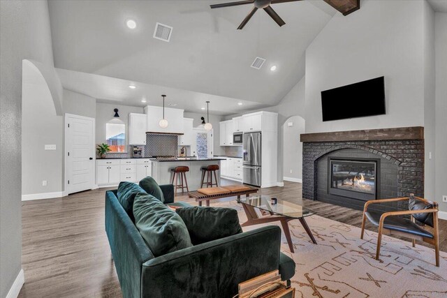 6803 52nd St, Lubbock, TX 79407 - living room with high vaulted ceiling, baseboards, wood finished floors, a ceiling fan, and a brick fireplace