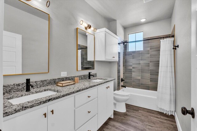 6803 52nd St, Lubbock, TX 79407 - full bathroom featuring wood finished floors, toilet, double vanity, and shower / tub combo with curtain