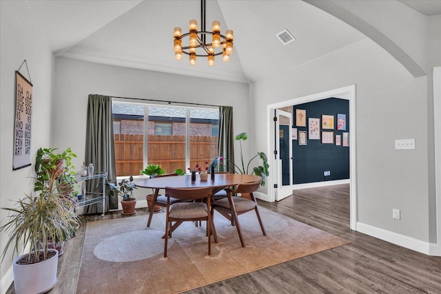 6803 52nd St, Lubbock, TX 79407 - dining space featuring arched walkways, a chandelier, baseboards, wood finished floors, and high vaulted ceiling