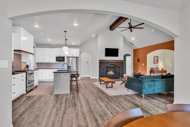 6803 52nd St, Lubbock, TX 79407 - living room featuring beamed ceiling, a ceiling fan, light wood finished floors, a lit fireplace, and recessed lighting