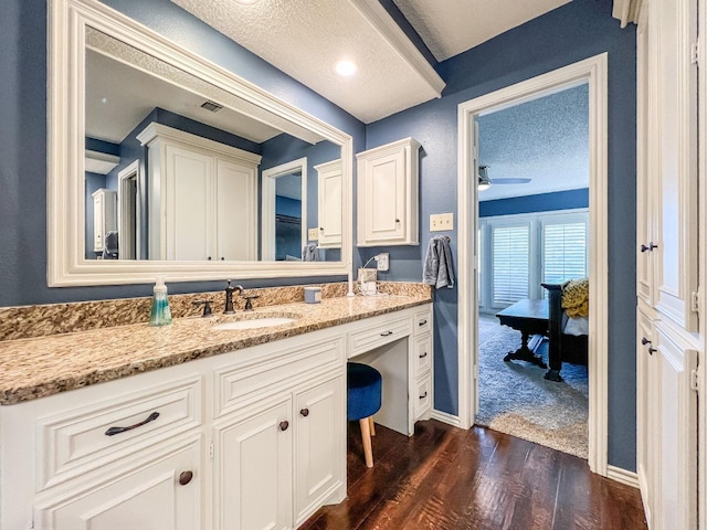 bathroom featuring ceiling fan, vanity, wood-type flooring, and a textured ceiling