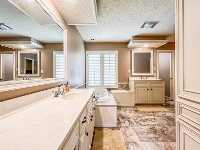 bathroom featuring vanity, a textured ceiling, and a tub