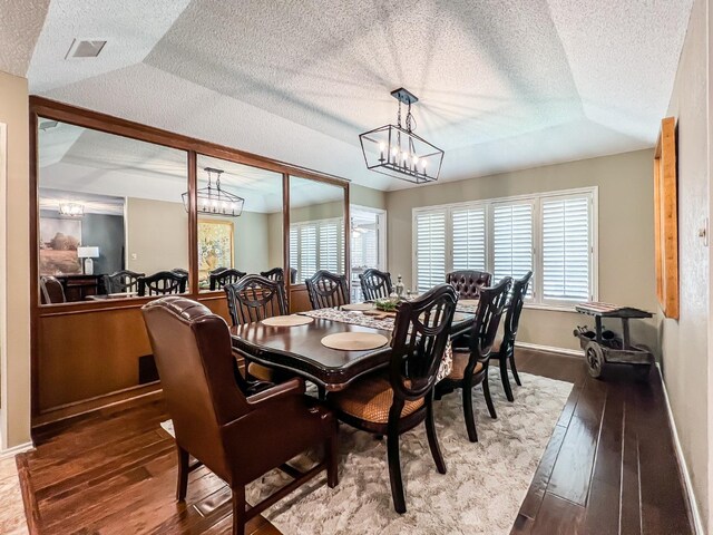 dining room featuring wood-type flooring, an inviting chandelier, and a textured ceiling