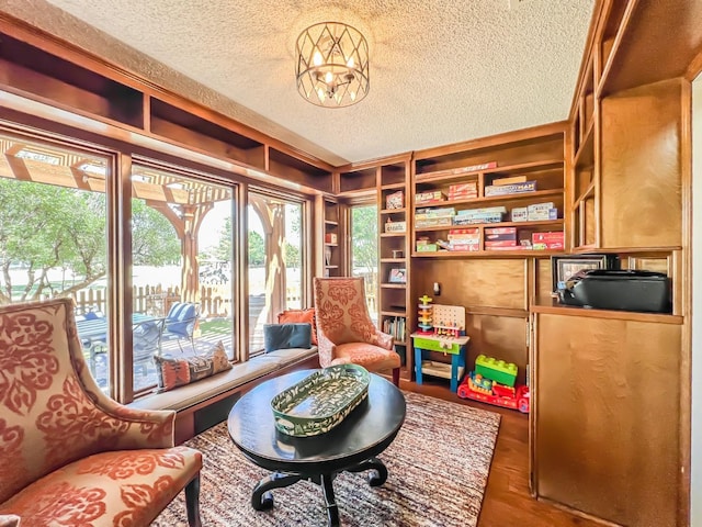 sitting room with an inviting chandelier, built in features, and a textured ceiling