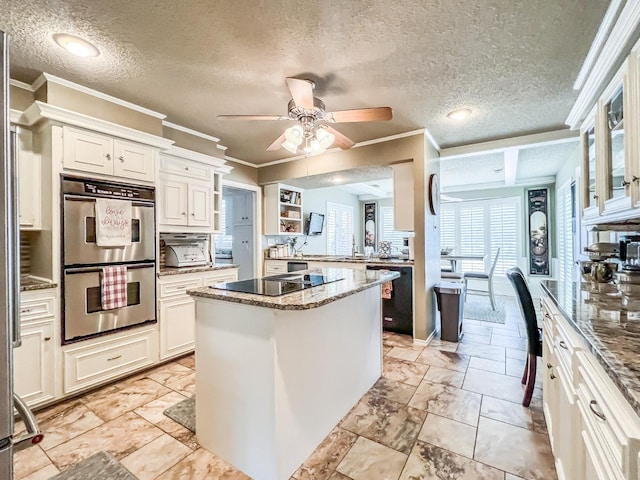 kitchen featuring white cabinets, dark stone counters, a kitchen island, and black appliances