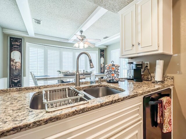 kitchen with dishwashing machine, ceiling fan, light stone counters, and a textured ceiling