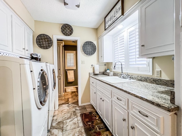 laundry room featuring cabinets, washer and dryer, sink, and a textured ceiling