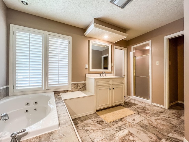 bathroom featuring vanity, independent shower and bath, and a textured ceiling