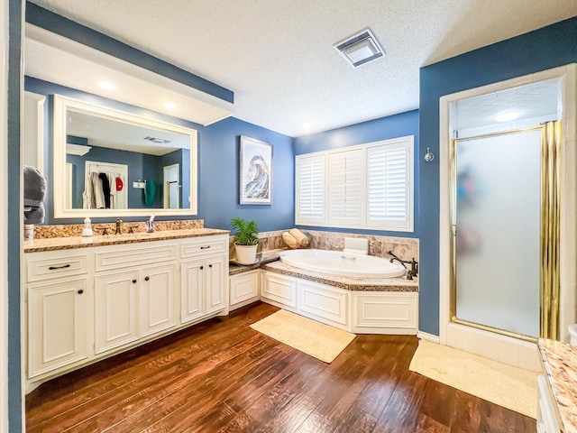 bathroom featuring shower with separate bathtub, hardwood / wood-style floors, vanity, and a textured ceiling