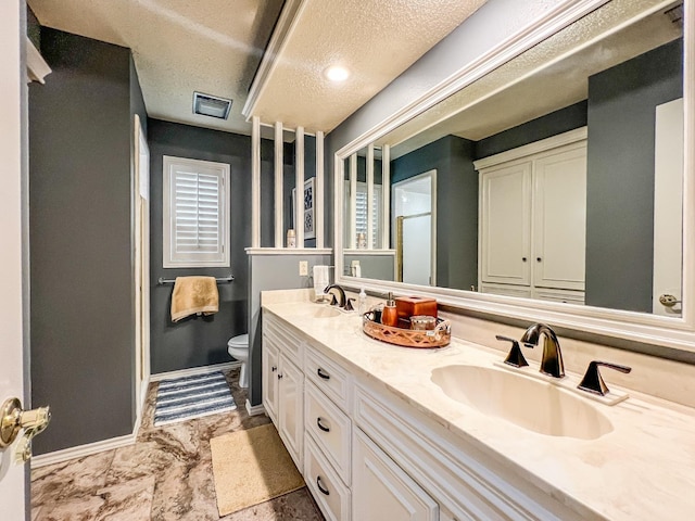 bathroom featuring vanity, a textured ceiling, and toilet