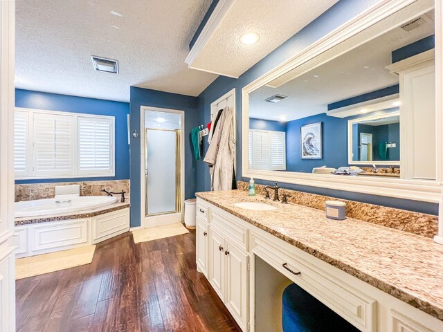 bathroom with shower with separate bathtub, wood-type flooring, vanity, and a textured ceiling