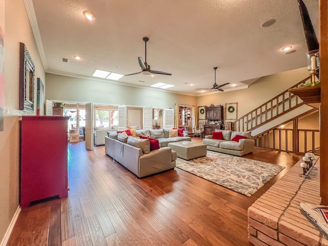 living room featuring hardwood / wood-style flooring, ornamental molding, a textured ceiling, and ceiling fan