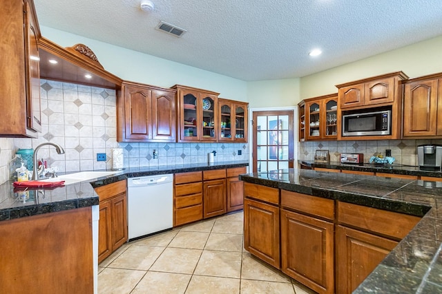 4306 Alcove Ave, Lubbock, TX 79407 - kitchen featuring glass insert cabinets, tile counters, visible vents, stainless steel microwave, and dishwasher