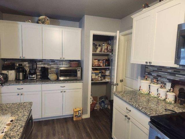 kitchen featuring stone countertops, white cabinets, dark hardwood / wood-style flooring, and decorative backsplash