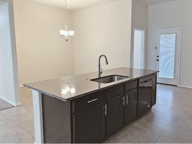 kitchen with sink, dishwasher, pendant lighting, light stone countertops, and a kitchen island with sink