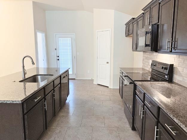 kitchen with lofted ceiling, sink, dark stone countertops, black electric range, and decorative backsplash