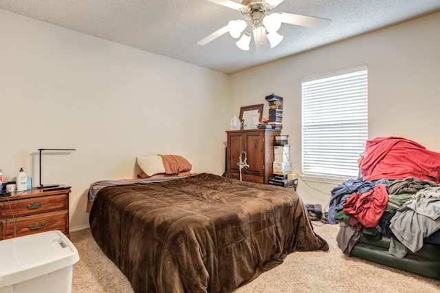 bedroom with ceiling fan, carpet floors, and a textured ceiling