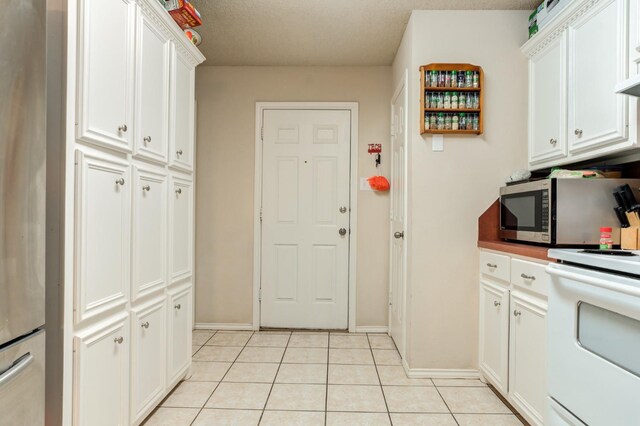 kitchen featuring white cabinetry, light tile patterned floors, and stove