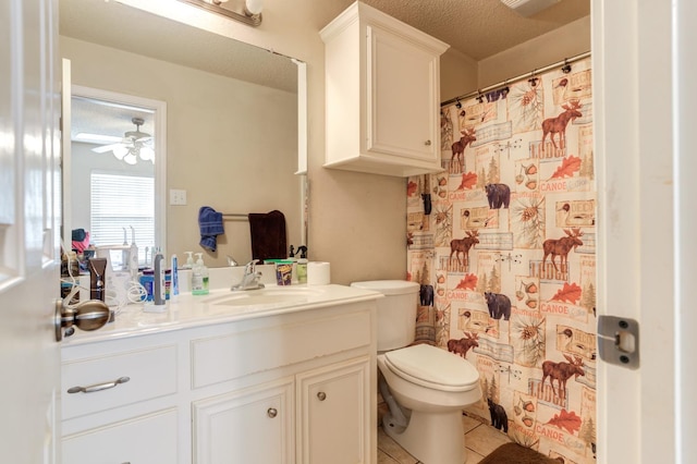 bathroom featuring tile patterned flooring, vanity, ceiling fan, toilet, and a textured ceiling