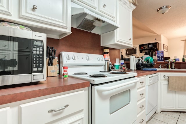 kitchen featuring sink, a textured ceiling, light tile patterned floors, white appliances, and white cabinets