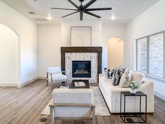 3630 120th St, Lubbock, TX 79423 - living area featuring arched walkways, a ceiling fan, wood finished floors, a stone fireplace, and baseboards