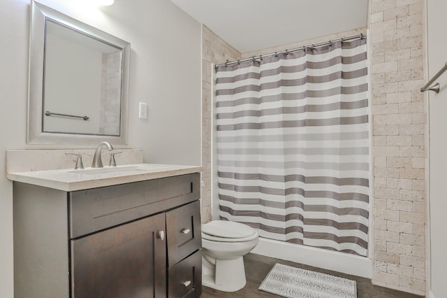 bathroom with walk in shower, toilet, wood-type flooring, vanity, and brick wall