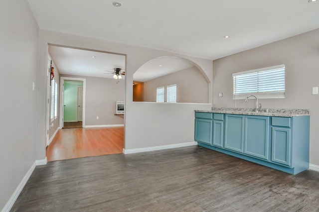 kitchen featuring heating unit, sink, dark wood-type flooring, ceiling fan, and blue cabinetry