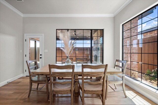 dining area with hardwood / wood-style floors, a wealth of natural light, and ornamental molding