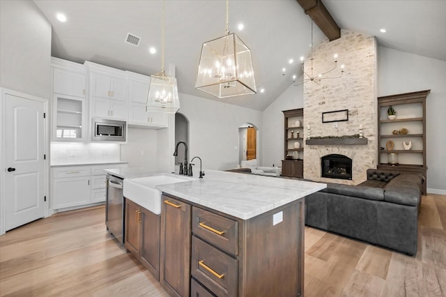 kitchen with pendant lighting, light hardwood / wood-style flooring, white cabinetry, a kitchen island with sink, and stainless steel appliances