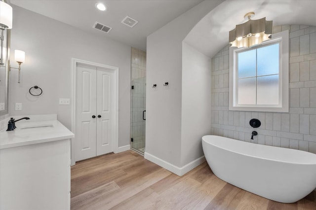 bathroom with hardwood / wood-style flooring, lofted ceiling, vanity, and separate shower and tub