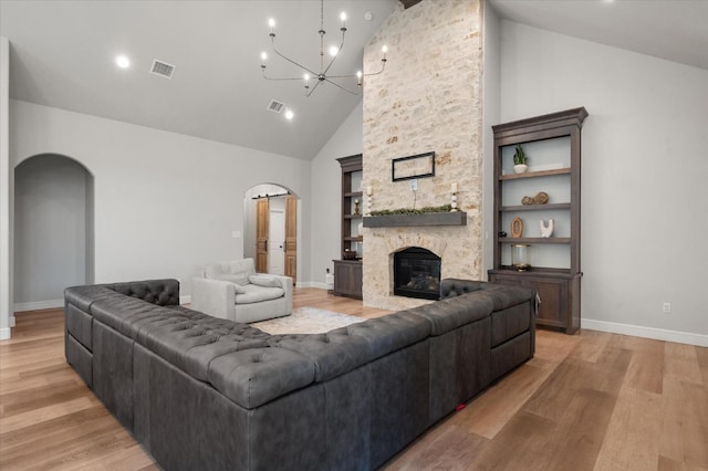 living room with a notable chandelier, a fireplace, and light hardwood / wood-style floors