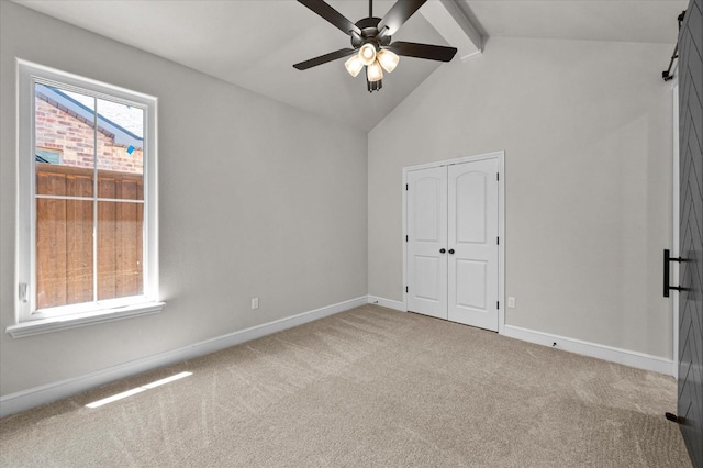 unfurnished bedroom featuring vaulted ceiling with beams, a closet, ceiling fan, and carpet flooring