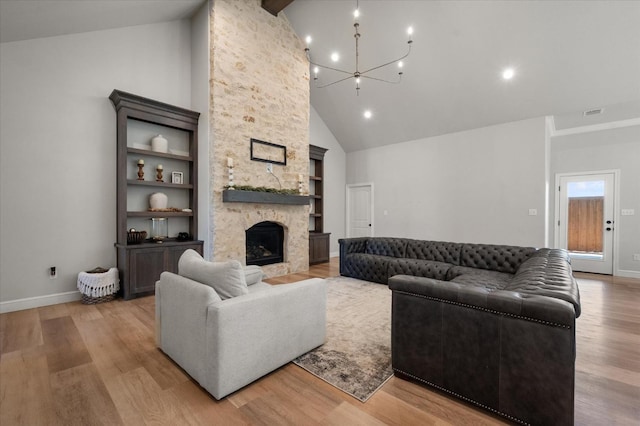 living room with built in features, high vaulted ceiling, a fireplace, a chandelier, and light wood-type flooring