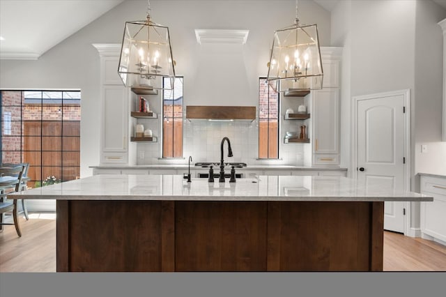 kitchen featuring pendant lighting, white cabinetry, and light stone countertops