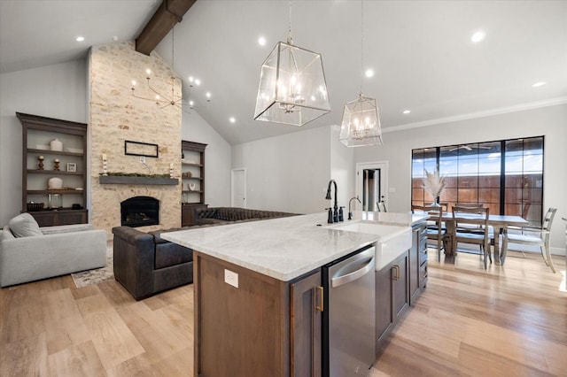 kitchen featuring hanging light fixtures, an island with sink, stainless steel dishwasher, and light hardwood / wood-style floors