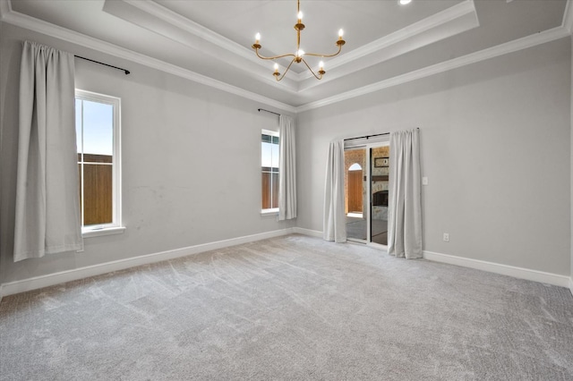 unfurnished room with carpet floors, ornamental molding, a raised ceiling, and a chandelier