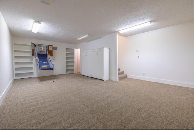 below grade area featuring light colored carpet, baseboards, a textured ceiling, and stairway
