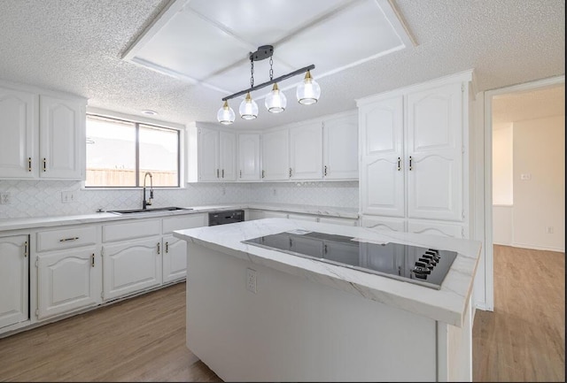 kitchen featuring a sink, decorative backsplash, light wood-style floors, black electric cooktop, and white cabinets