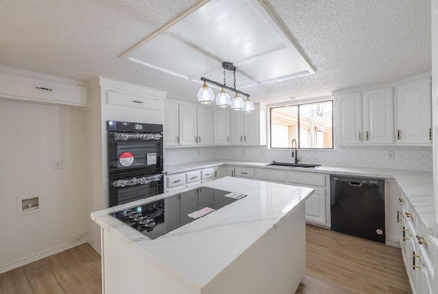 kitchen with white cabinets, light wood finished floors, a sink, black appliances, and a textured ceiling