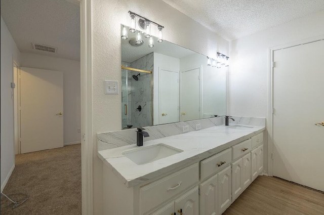 bathroom with a shower stall, a sink, visible vents, and a textured ceiling