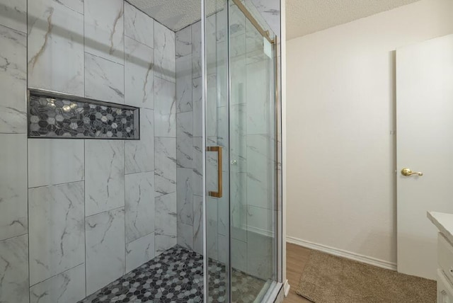 full bath with wood finished floors, a marble finish shower, a textured ceiling, and vanity