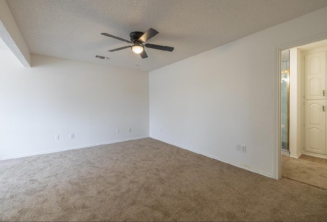 carpeted empty room featuring a textured ceiling, visible vents, a ceiling fan, and baseboards