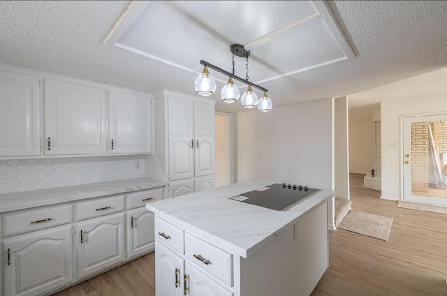 kitchen featuring white cabinets, light wood-type flooring, a center island, decorative backsplash, and black electric stovetop