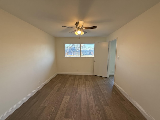 spare room featuring ceiling fan, dark wood-type flooring, and baseboards