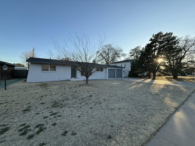 ranch-style home with driveway, fence, and brick siding