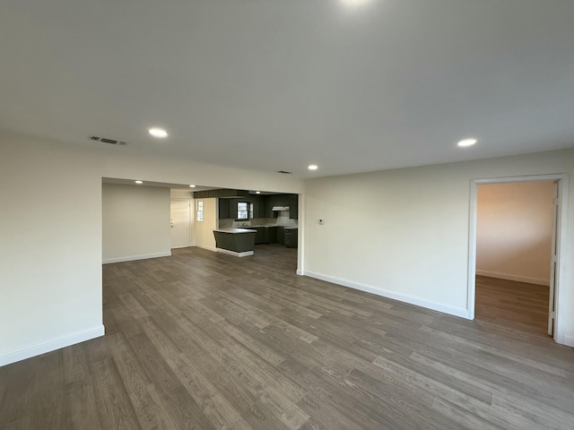 unfurnished living room with baseboards, visible vents, dark wood finished floors, and recessed lighting