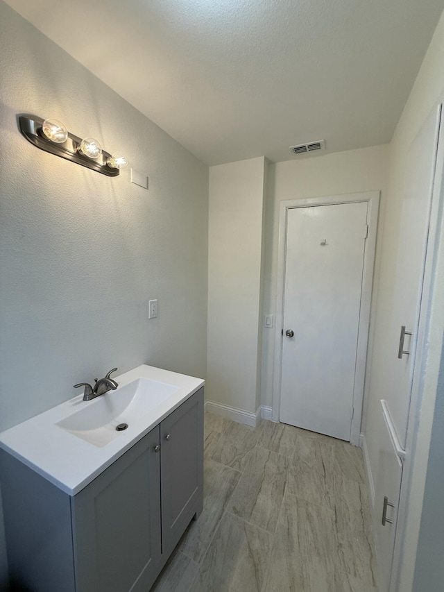 bathroom with baseboards, visible vents, and vanity