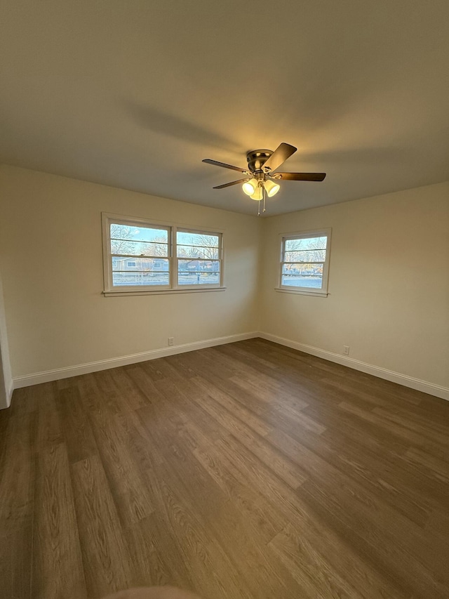 spare room featuring dark wood-style floors, ceiling fan, and baseboards